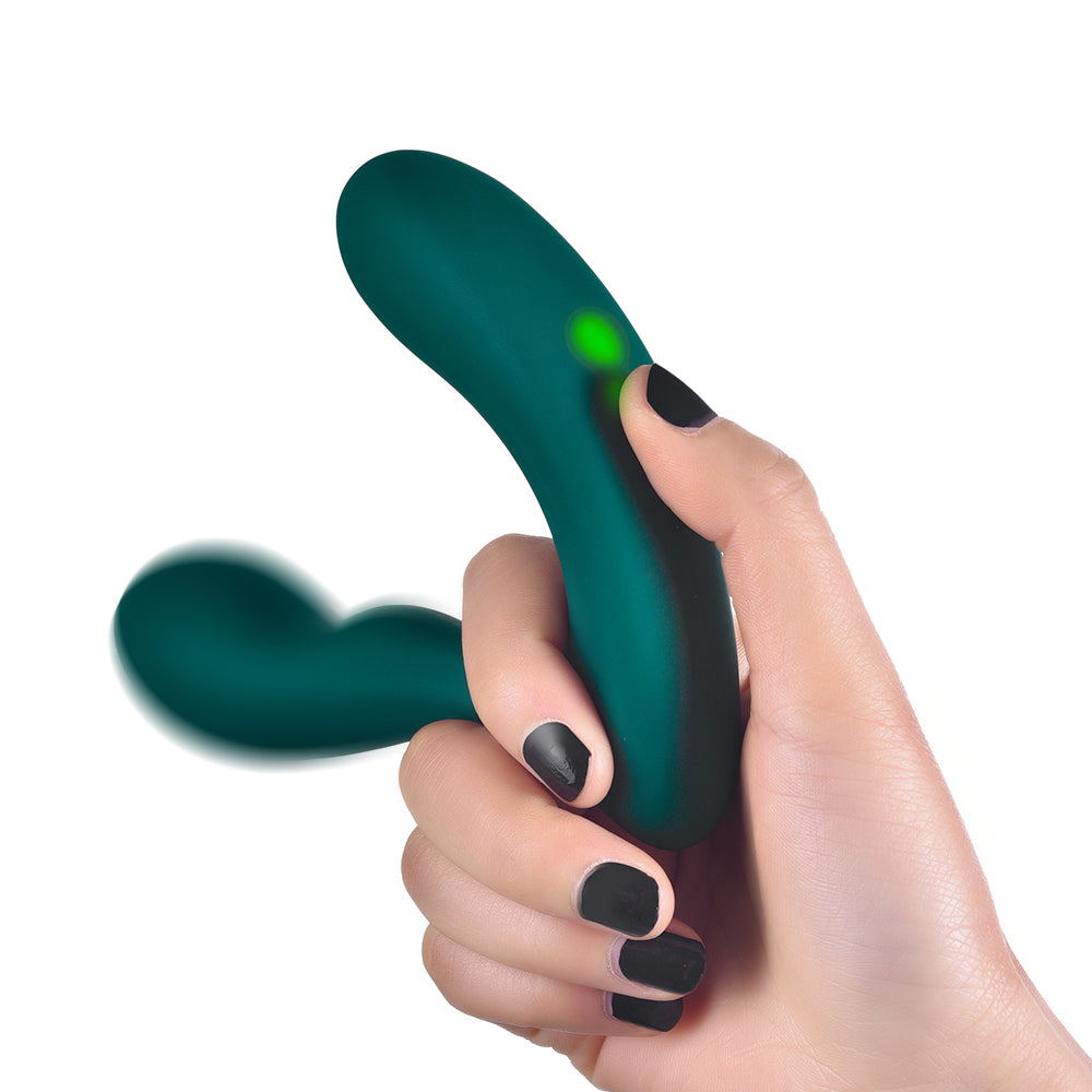 Hand holding a dark green dual-arm vibrator with an illuminated indicator against a white background.
