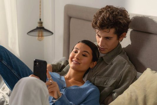 Couple in bed looking at a smartphone together, couples vibrators with app and remote control