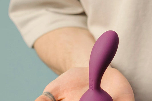 Purple vibrator resting on an open palm, vibrator tips for settings and controls